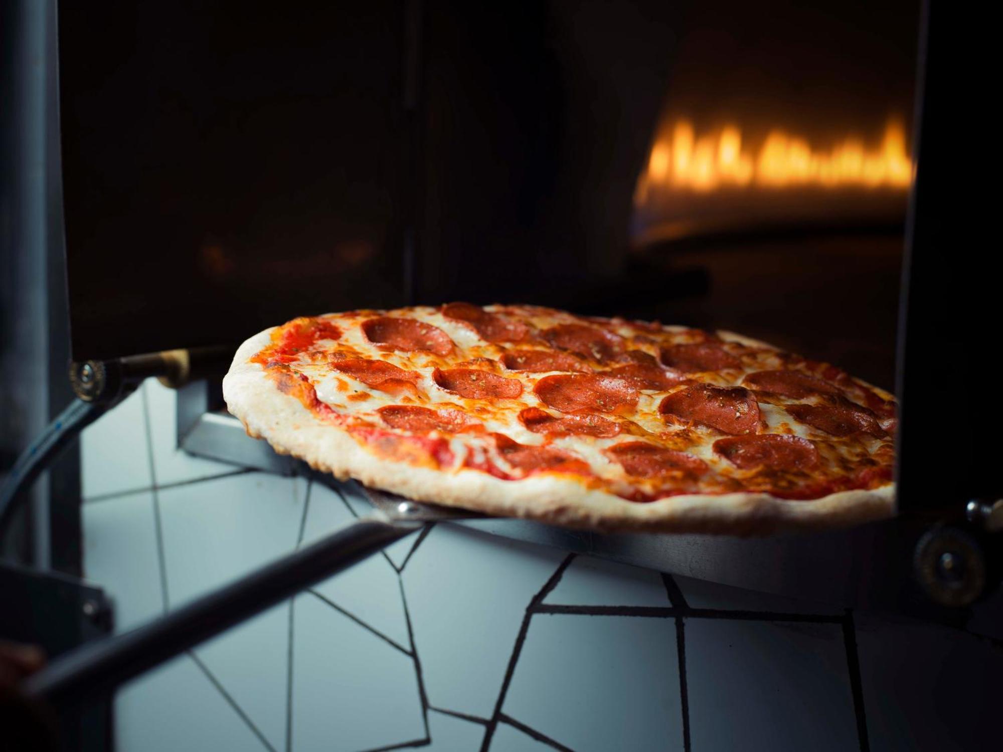 达曼喜来登会议中心酒店 外观 照片 Pizza being removed from a wood-fired oven